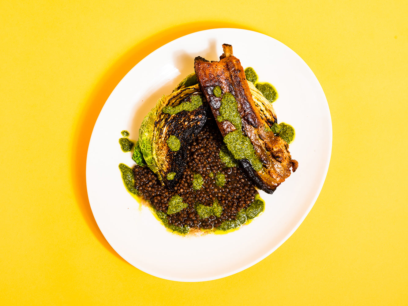 Cooked Bone In Skin On Pork Belly Chop with Lentils and Cabbage